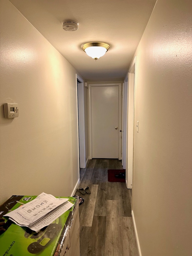 corridor featuring dark wood-style floors and baseboards