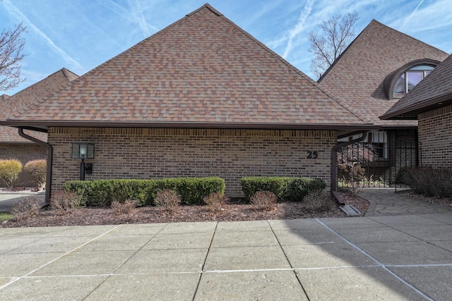 view of side of property with brick siding and roof with shingles