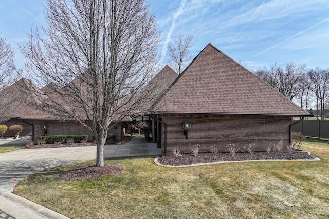 view of property exterior featuring brick siding, concrete driveway, a yard, and roof with shingles