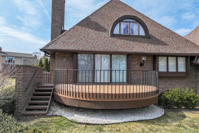 back of property with brick siding, a deck, a chimney, and a shingled roof