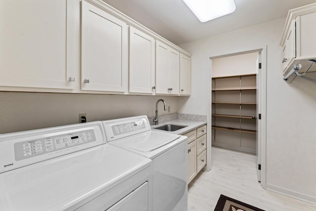 laundry area with washing machine and dryer, cabinet space, light wood-style flooring, and a sink