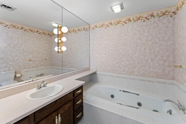 bathroom with visible vents, toilet, vanity, and a tub with jets