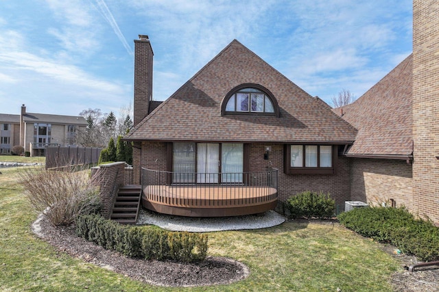 view of front of house with a front lawn, a chimney, brick siding, and a wooden deck