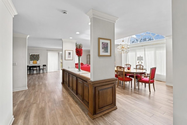 kitchen with light wood finished floors, brown cabinetry, crown molding, a chandelier, and tile counters