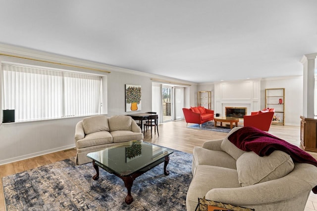 living room featuring a glass covered fireplace, crown molding, wood finished floors, and baseboards