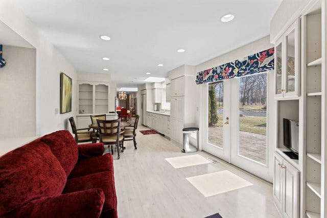 living area with recessed lighting, light wood-type flooring, a chandelier, and french doors