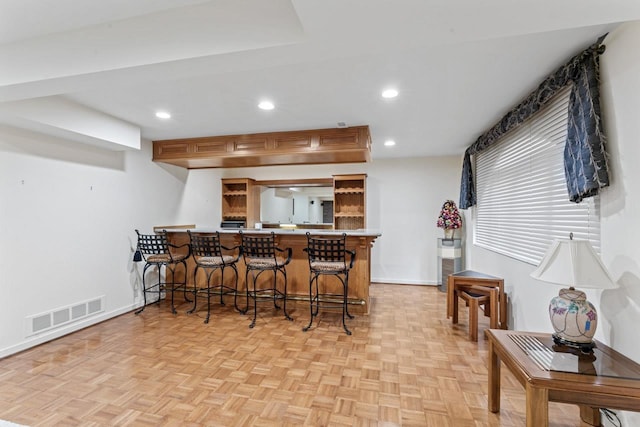 kitchen with visible vents, recessed lighting, a kitchen bar, and baseboards