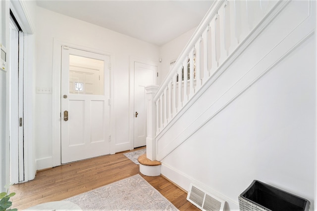 entrance foyer with visible vents, baseboards, light wood-style floors, and stairway