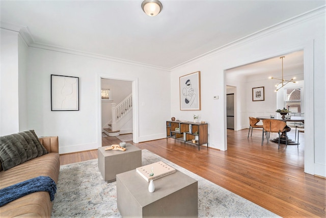 living area with stairway, a chandelier, wood finished floors, and ornamental molding