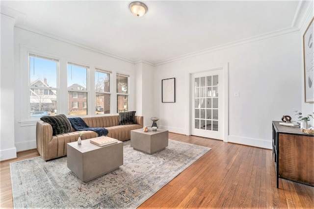 living area with baseboards, hardwood / wood-style floors, and ornamental molding