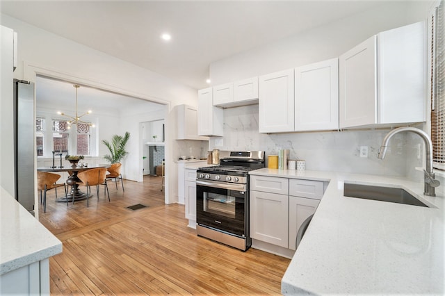 kitchen with visible vents, a sink, tasteful backsplash, stainless steel appliances, and light wood finished floors