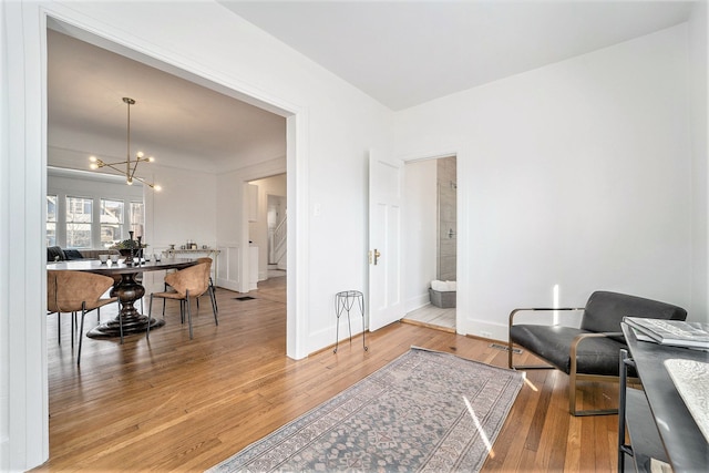 living area featuring baseboards, a notable chandelier, and light wood-style flooring