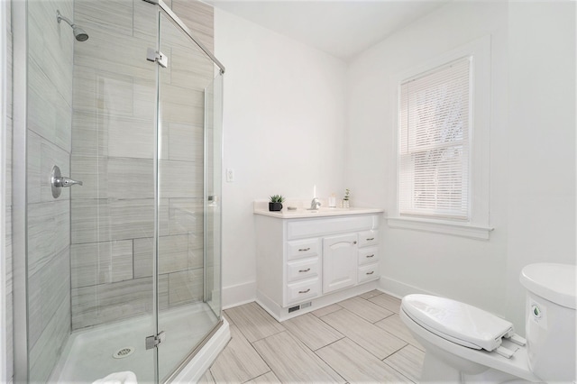 full bathroom featuring baseboards, toilet, vanity, and a shower stall