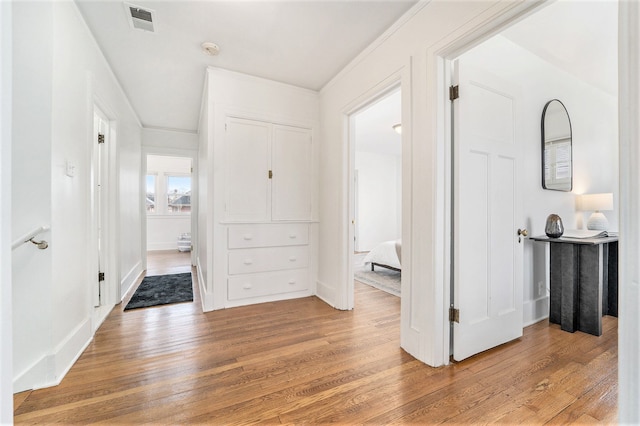 corridor featuring light wood-style flooring, baseboards, and visible vents