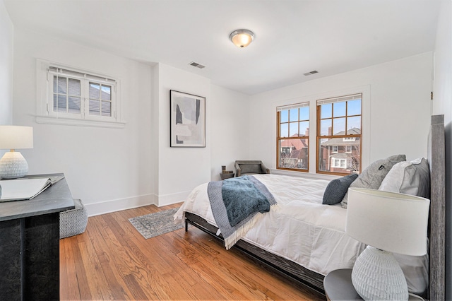 bedroom featuring visible vents, light wood-type flooring, and baseboards