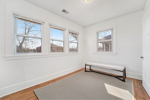 sitting room featuring visible vents, baseboards, wood finished floors, and ornamental molding