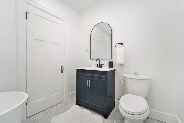 bathroom with vanity, baseboards, a soaking tub, tile patterned floors, and toilet