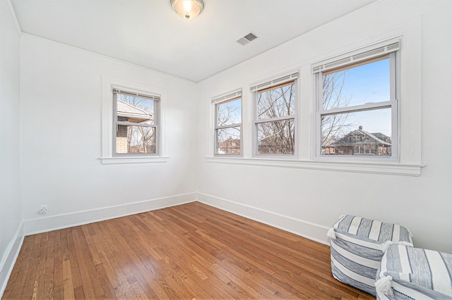 spare room featuring visible vents, a healthy amount of sunlight, baseboards, and wood-type flooring