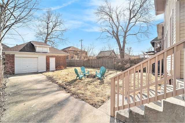 view of yard with an outbuilding, driveway, fence, a fire pit, and stairs