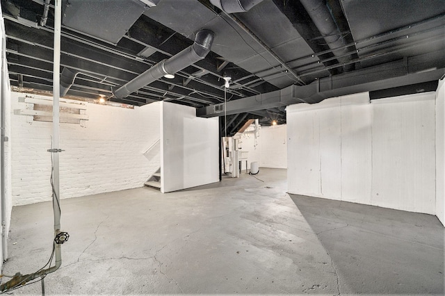 unfinished basement featuring stairway and brick wall