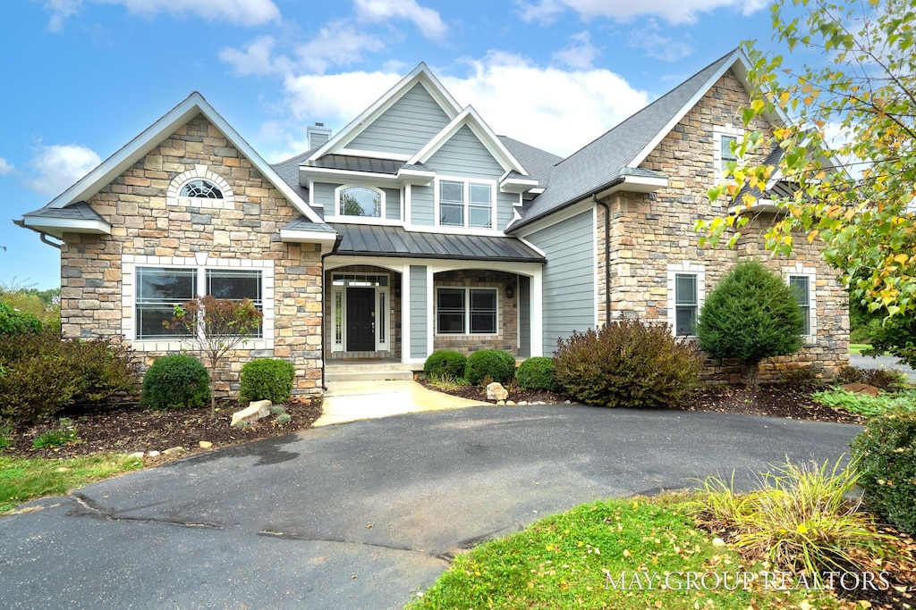 craftsman inspired home featuring a chimney, covered porch, metal roof, and a standing seam roof