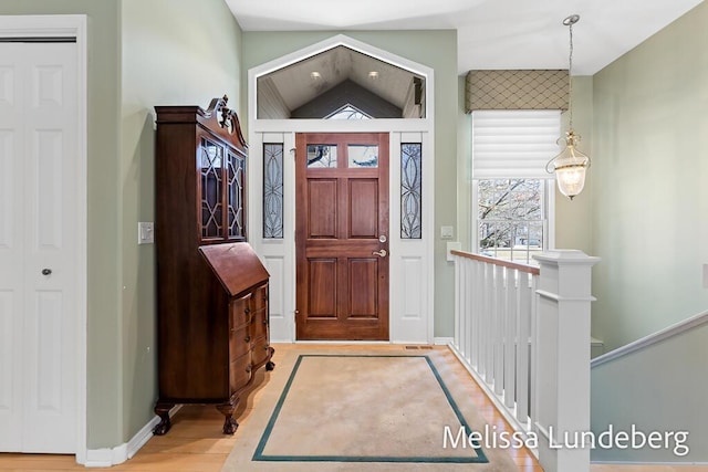 foyer with wood finished floors, baseboards, and vaulted ceiling