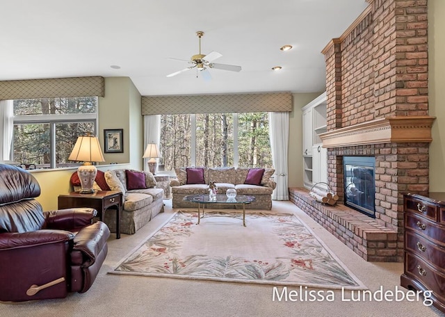 carpeted living room featuring a brick fireplace and a ceiling fan