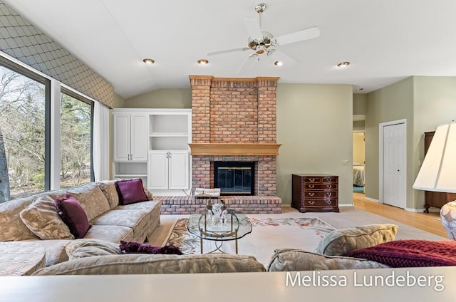 living room with light wood-style flooring, a ceiling fan, a fireplace, baseboards, and vaulted ceiling