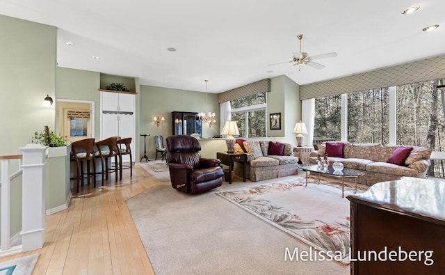 living room with light wood finished floors, recessed lighting, and ceiling fan with notable chandelier