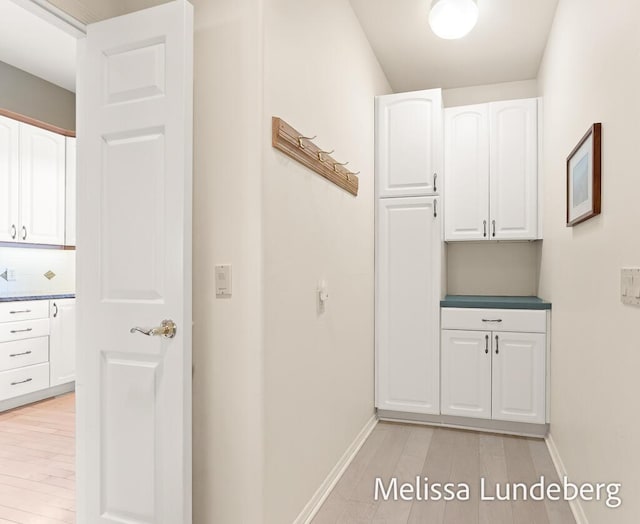 hallway featuring light wood-type flooring and baseboards