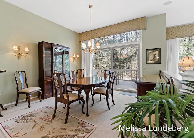 dining room featuring light carpet, plenty of natural light, baseboards, and an inviting chandelier