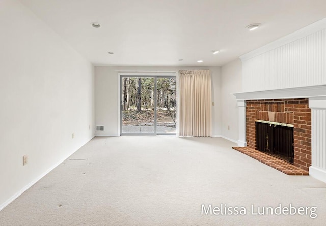 unfurnished living room with a brick fireplace, baseboards, visible vents, and carpet floors