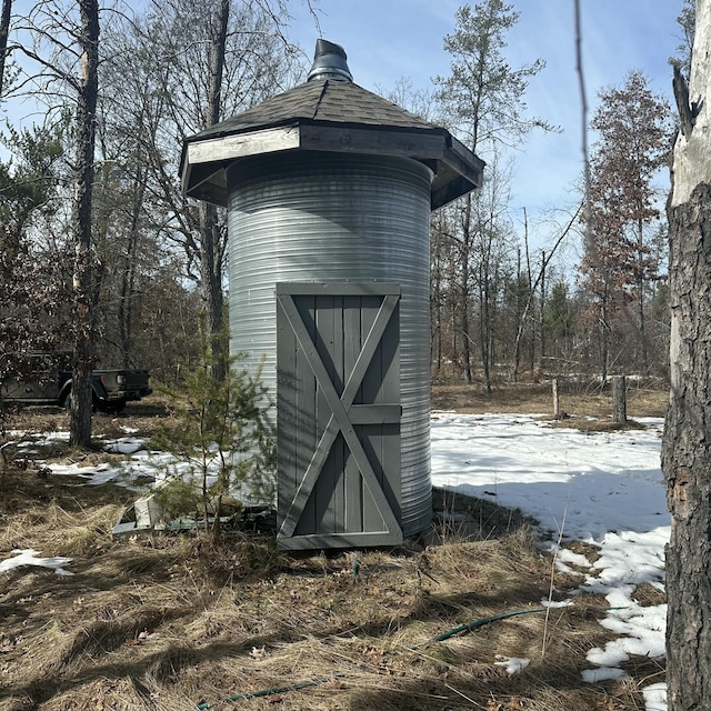 snow covered structure with a storage shed and an outdoor structure