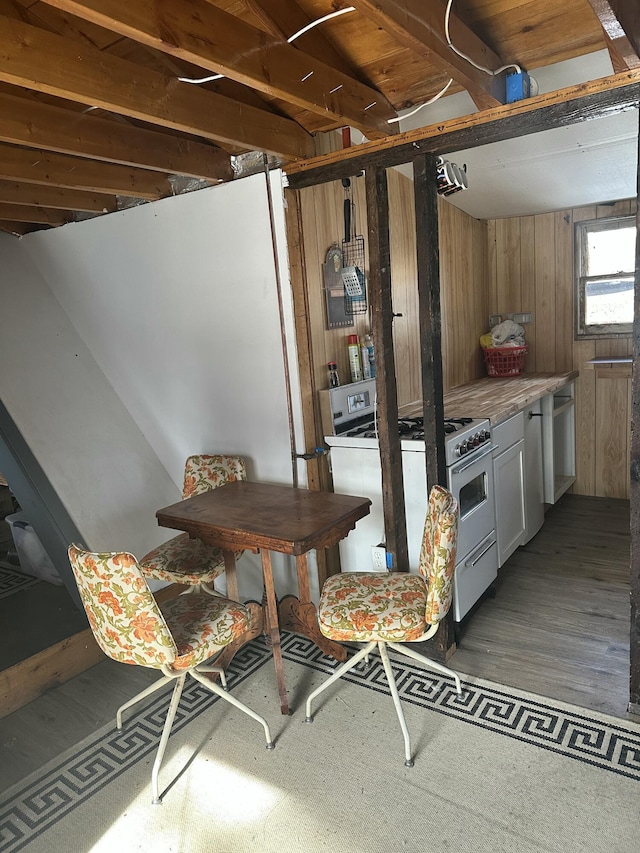 kitchen featuring range with gas stovetop, light countertops, wooden walls, and wood finished floors