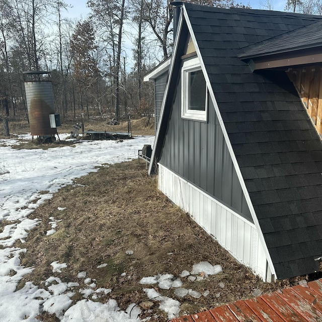 snow covered property featuring a shingled roof