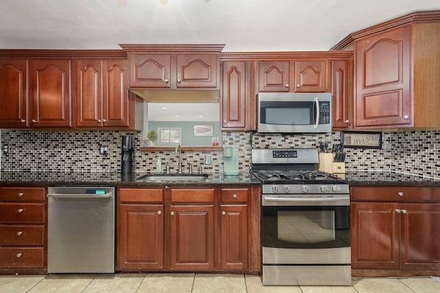 kitchen featuring tasteful backsplash, dark stone countertops, stainless steel appliances, and a sink