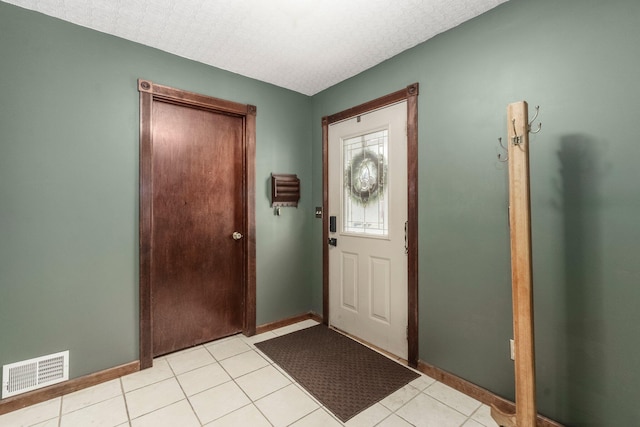 foyer entrance with light tile patterned flooring, visible vents, a textured ceiling, and baseboards