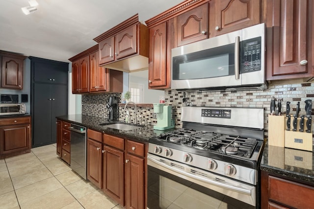 kitchen featuring a sink, tasteful backsplash, dark stone counters, appliances with stainless steel finishes, and light tile patterned floors