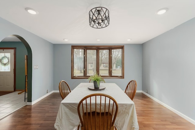 dining space featuring recessed lighting, wood finished floors, arched walkways, and baseboards