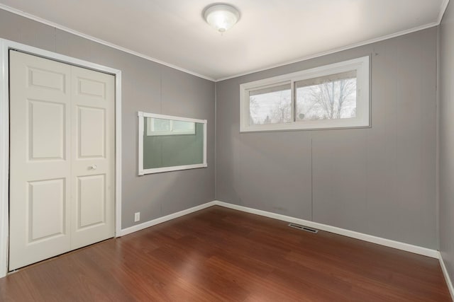 interior space with dark wood-type flooring, baseboards, visible vents, and ornamental molding