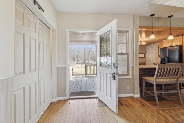 foyer with light wood-type flooring, a barn door, and baseboards