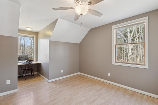 additional living space with baseboards, plenty of natural light, lofted ceiling, and wood finished floors