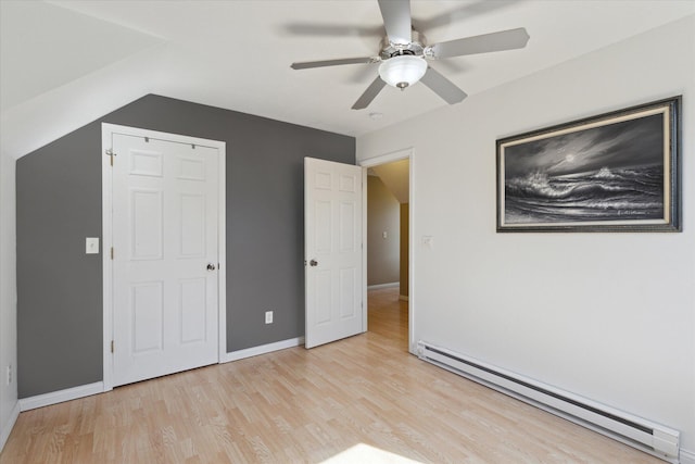 unfurnished bedroom featuring a baseboard radiator, baseboards, a ceiling fan, and light wood finished floors