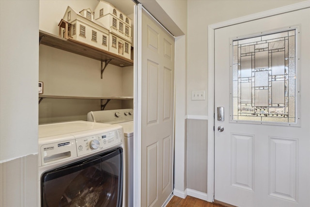 clothes washing area with baseboards, wood finished floors, laundry area, and washing machine and clothes dryer