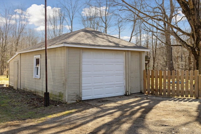 detached garage with fence and dirt driveway