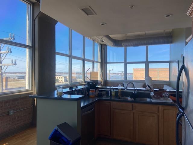 kitchen with dishwashing machine, wood finished floors, visible vents, freestanding refrigerator, and dark countertops