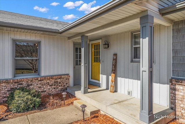 doorway to property featuring covered porch and roof with shingles