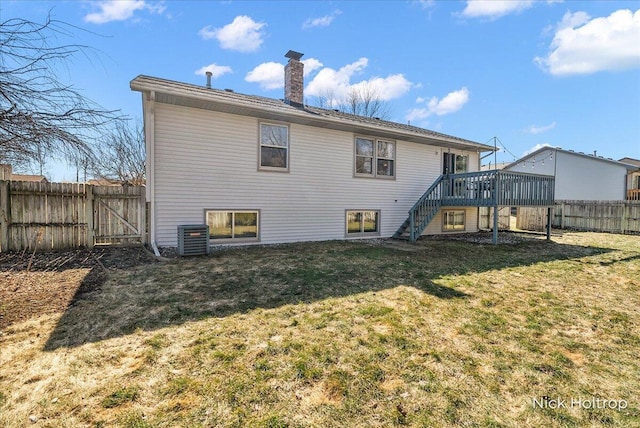 back of house with stairway, a gate, a fenced backyard, a chimney, and a lawn