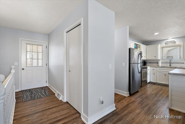 kitchen featuring dark wood finished floors, white cabinets, appliances with stainless steel finishes, and a sink