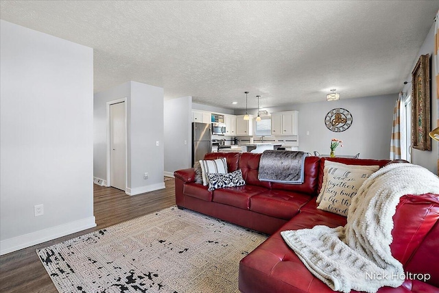 living room with a textured ceiling, baseboards, and wood finished floors